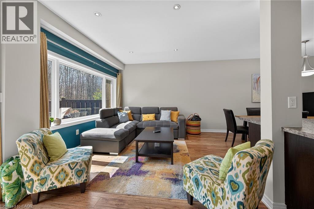 Spacious living area featuring large picture windows, recessed lighting, wood-finish flooring, and a neutral color palette - 149 Kinsman Drive, Binbrook, ON