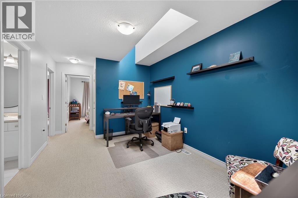 Carpeted hallway featuring a vaulted ceiling with skylight, wall-mounted shelving, overhead lighting, and white trim - 149 Kinsman Drive, Binbrook, ON