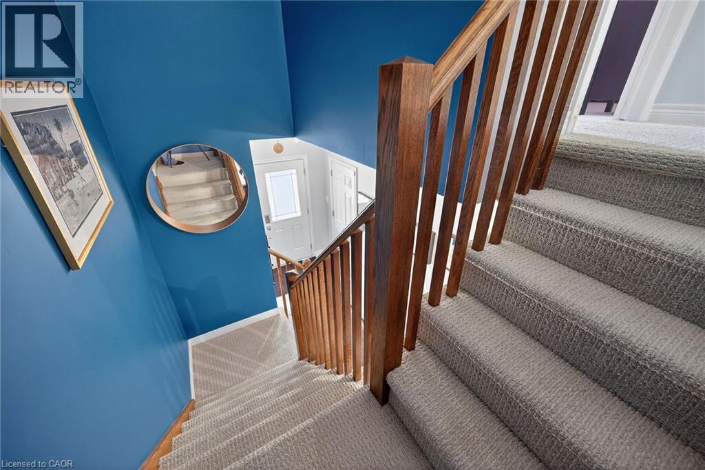 Carpeted staircase with wood-finish balusters and handrail - 149 Kinsman Drive, Binbrook, ON
