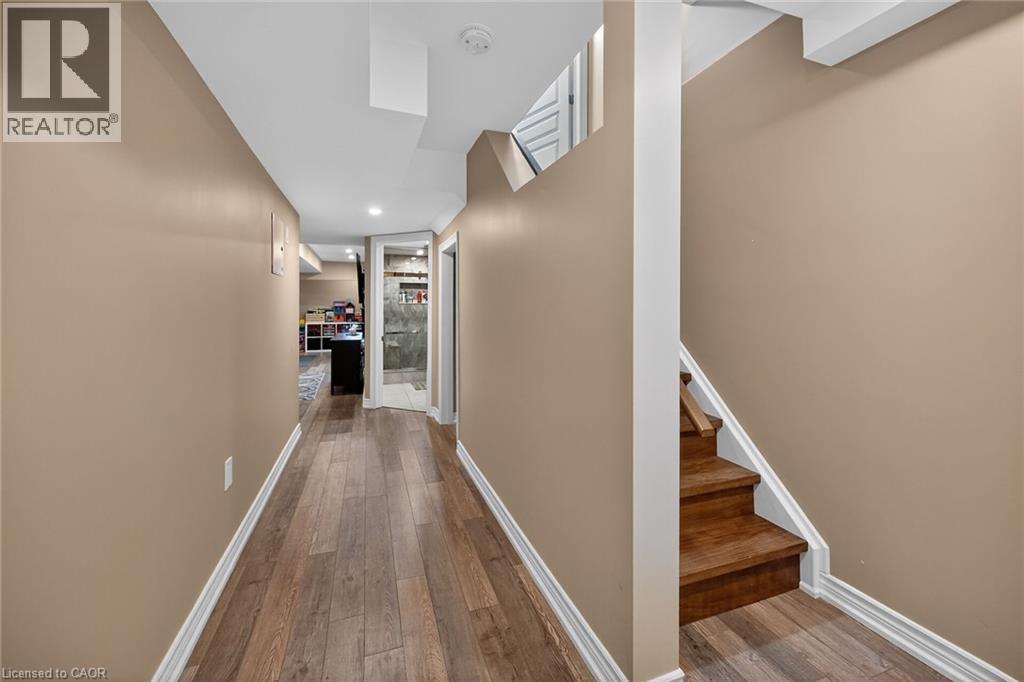Lower-level hallway featuring wood-finish flooring, recessed lighting, and a partial staircase with wood treads and white risers - 149 Kinsman Drive, Binbrook, ON