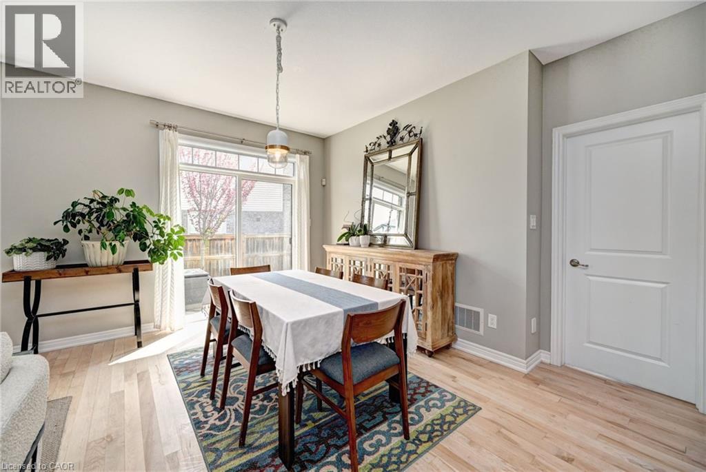 Dining space featuring light wood-finish flooring, a sliding glass door, and a contemporary pendant light fixture - 219 Falconridge Drive, Kitchener, ON - Indoor Photo Showing Dining Room