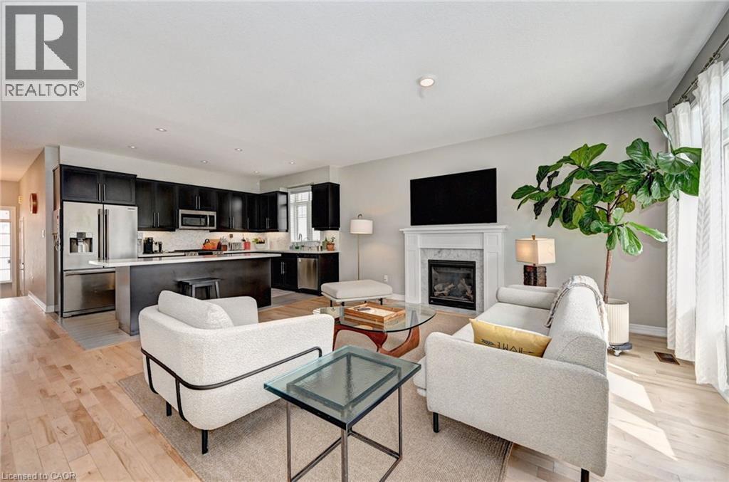 Open-concept living space featuring light wood-finish flooring, a contemporary fireplace with a white mantel, and recessed ceiling lighting - 219 Falconridge Drive, Kitchener, ON - Indoor Photo Showing Living Room With Fireplace