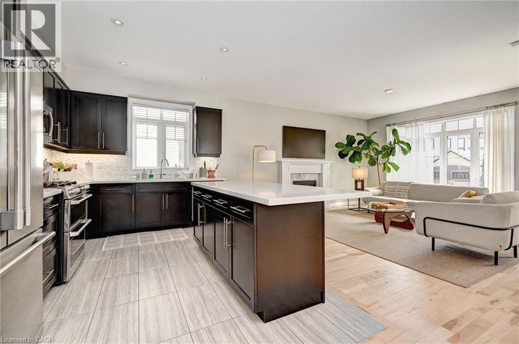 Open-concept living space featuring a modern kitchen with dark wood cabinetry, stainless steel appliances, and a central island with a light-colored countertop - 219 Falconridge Drive, Kitchener, ON - Indoor Photo Showing Kitchen