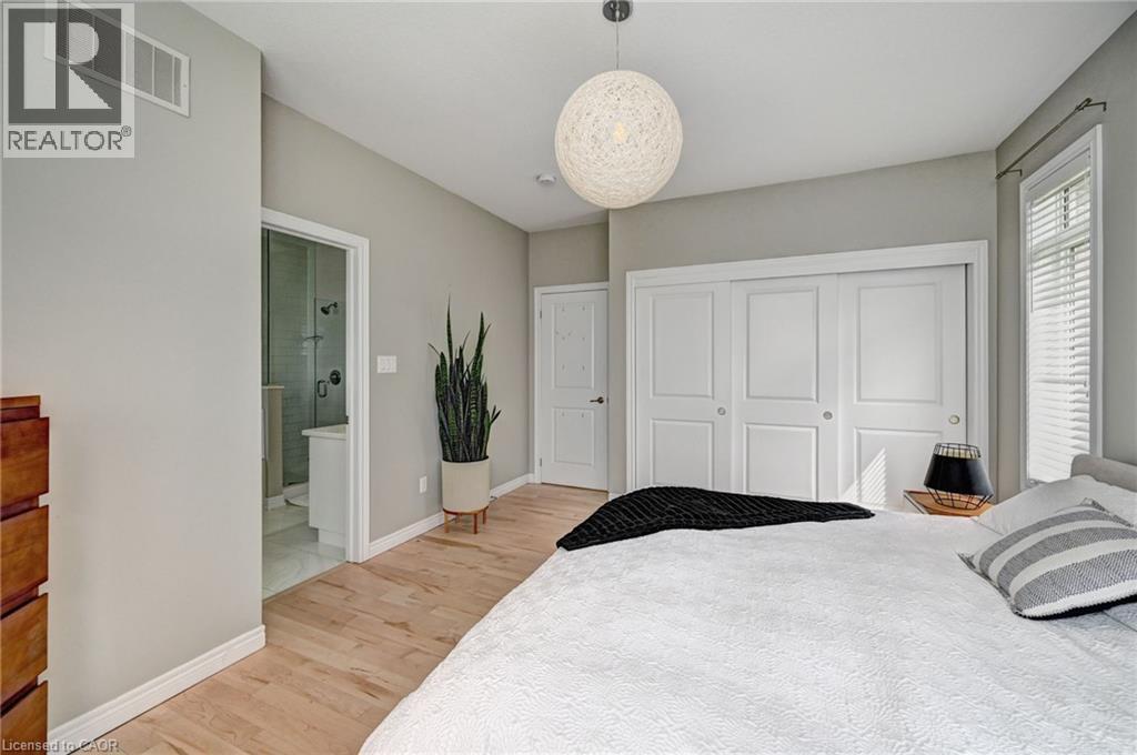 Light wood-finish flooring with white baseboards, a spherical pendant light fixture, and a three-panel sliding closet with white doors - 219 Falconridge Drive, Kitchener, ON - Indoor Photo Showing Bedroom