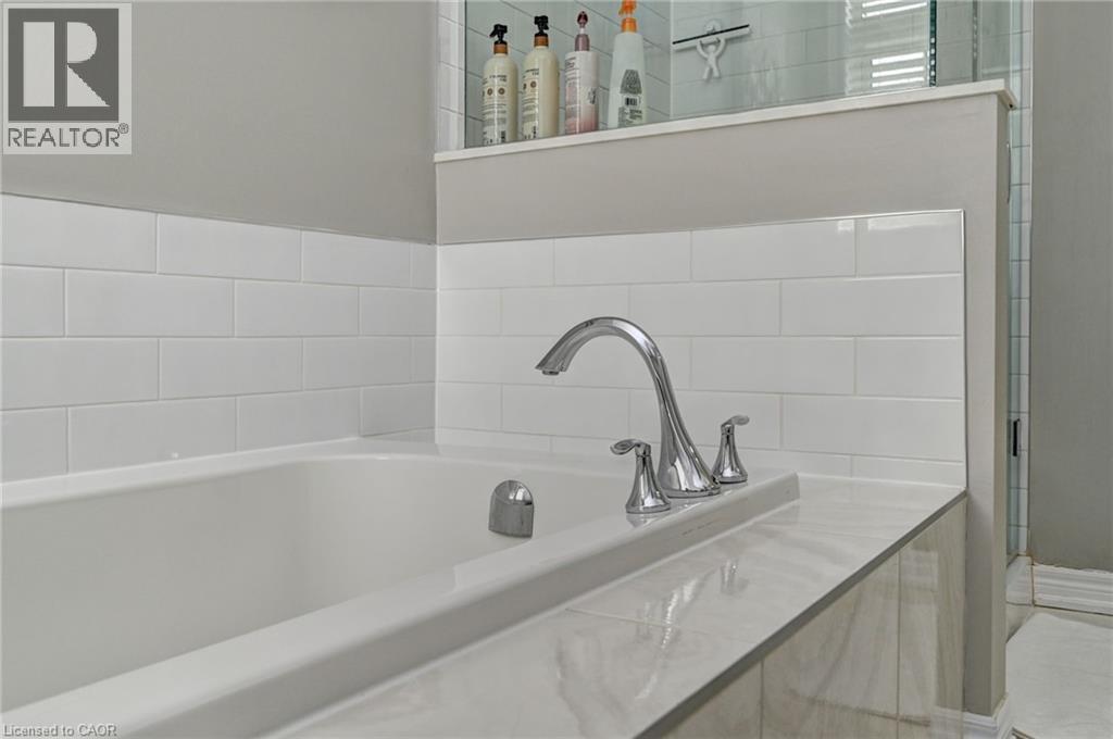 Soaking tub with subway tile surround, chrome fixtures, and a tiled deck - 219 Falconridge Drive, Kitchener, ON - Indoor Photo Showing Bathroom