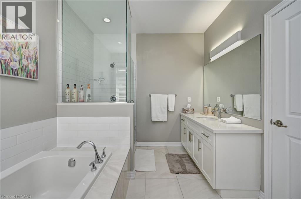 Contemporary bathroom featuring a freestanding tub, glass-enclosed shower, white subway tile accents, and a dual-sink vanity with a large mirror - 219 Falconridge Drive, Kitchener, ON - Indoor Photo Showing Bathroom