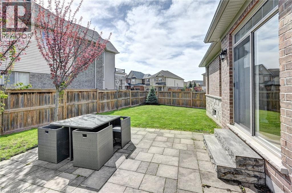 Paved patio area with a sliding glass door entry to the property, featuring a stone veneer foundation and brick exterior - 219 Falconridge Drive, Kitchener, ON - Outdoor With Deck Patio Veranda