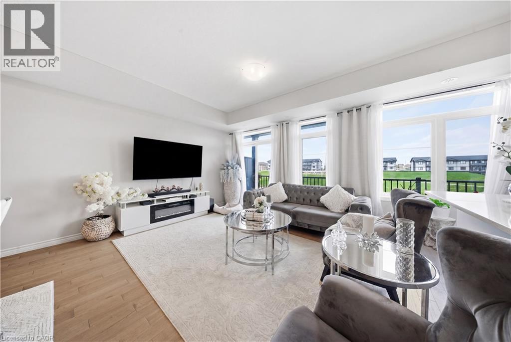 Bright living space featuring wood-finish flooring, recessed lighting, and large windows - 176 Wheat Lane, Kitchener, ON - Indoor Photo Showing Living Room