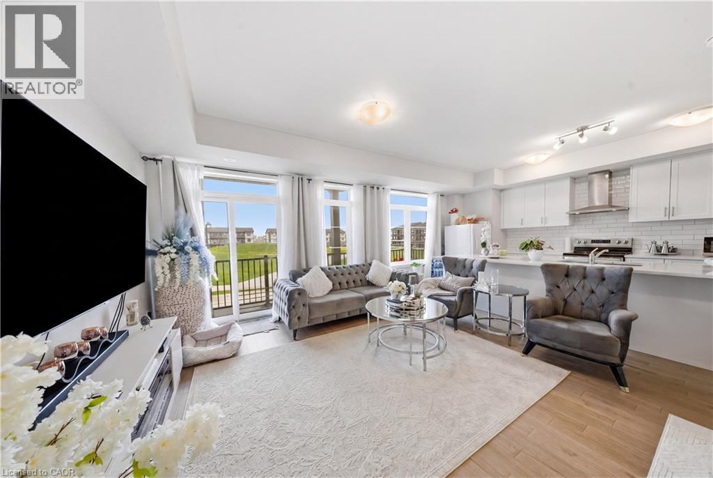 Open-concept living space featuring a kitchen with white cabinetry, stainless steel appliances, and a subway tile backsplash - 176 Wheat Lane, Kitchener, ON - Indoor Photo Showing Living Room