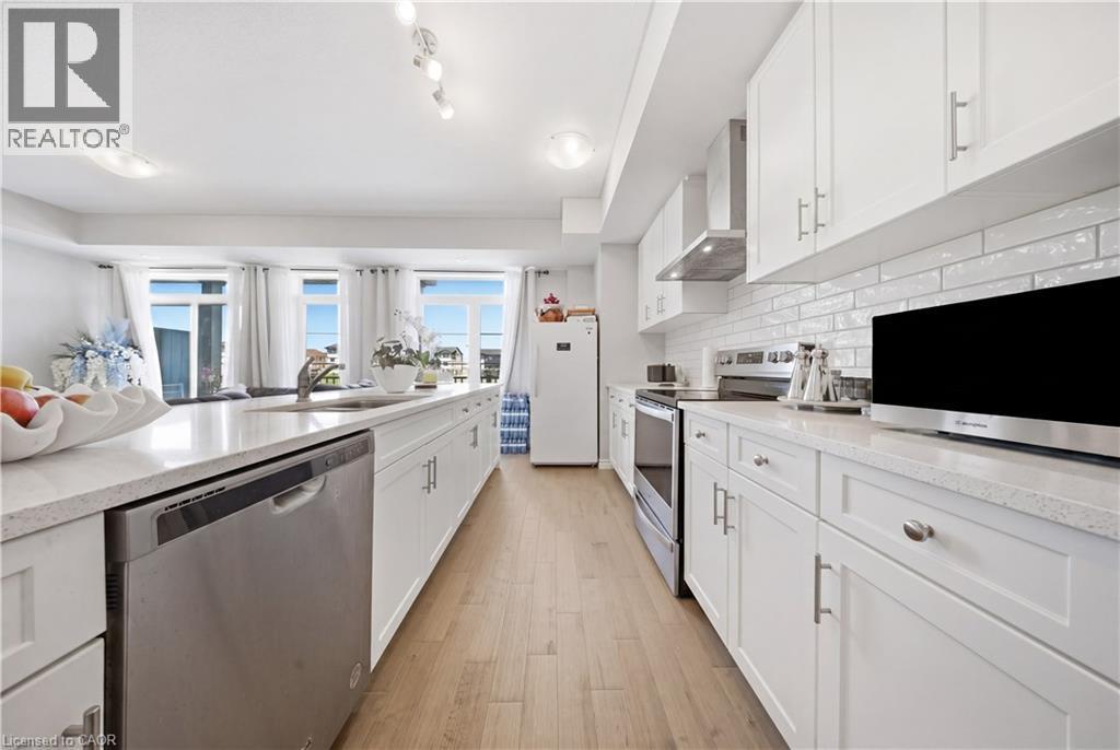 Contemporary kitchen featuring white cabinetry, light-toned wood-finish flooring, and white subway tile backsplash - 176 Wheat Lane, Kitchener, ON - Indoor Photo Showing Kitchen With Upgraded Kitchen