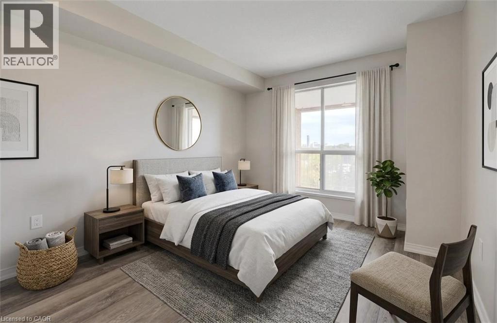 Room featuring a large window, light-colored walls, wood-finish flooring, and a textured area rug - 1414 E King Street E Unit# 802, Kitchener, ON - Indoor Photo Showing Bedroom