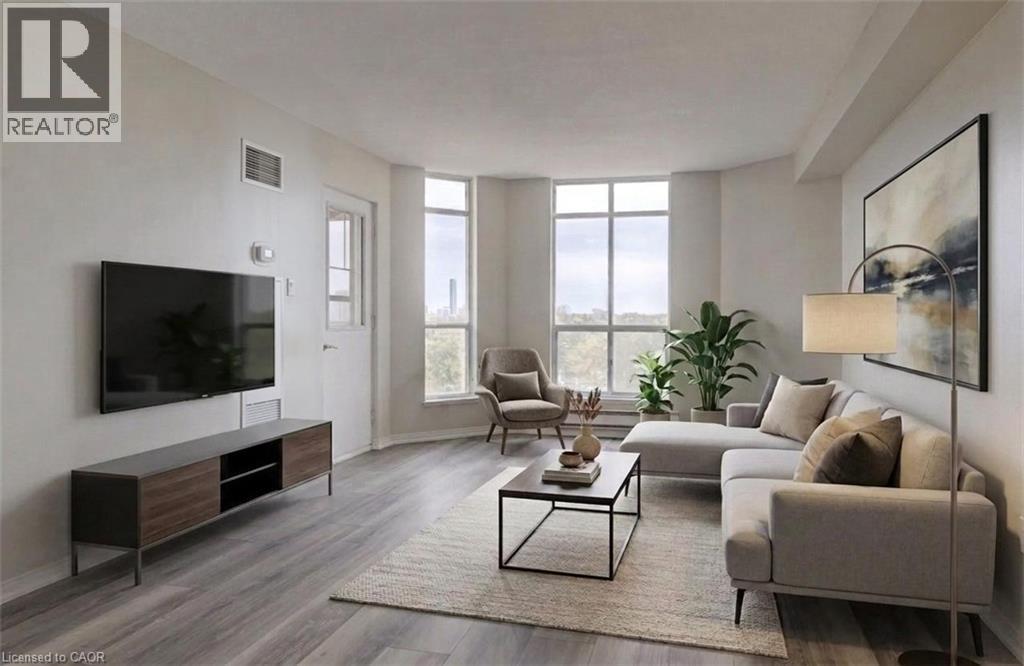 Bright living space featuring expansive windows, wood-finish flooring, light-toned walls, a built-in air vent, and a white door with transom window - 1414 E King Street E Unit# 802, Kitchener, ON - Indoor Photo Showing Living Room