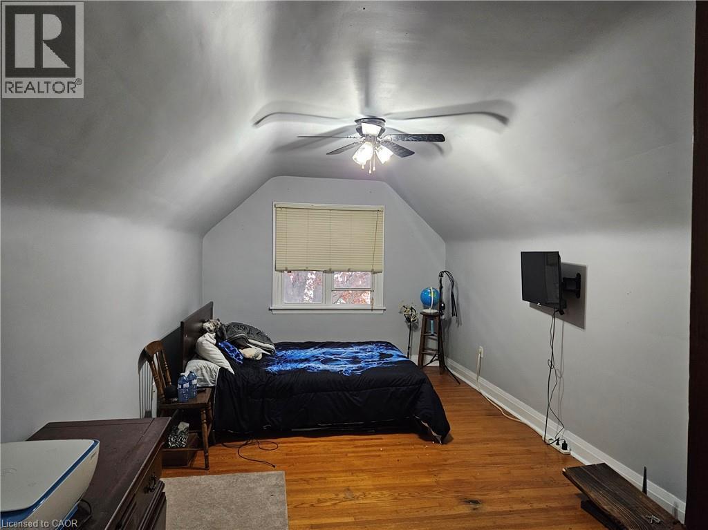 Room featuring sloped ceilings, a window with blinds, wood-finish flooring, a ceiling fan, and light gray wall paint - 75 Barons Avenue S, Hamilton, ON - Indoor Photo Showing Bedroom