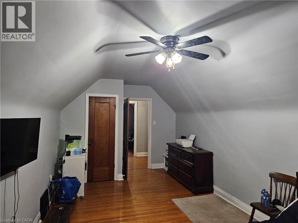Attic room featuring a ceiling fan with integrated lighting, wood-finish flooring, and sloped ceilings - 75 Barons Avenue S, Hamilton, ON - Indoor