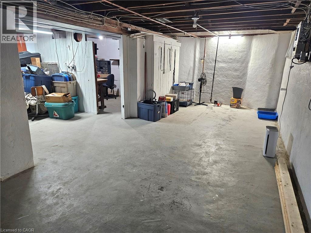 Unfinished basement featuring exposed ceiling joists, concrete flooring, painted stone walls, and a separate partially enclosed area - 75 Barons Avenue S, Hamilton, ON - Indoor Photo Showing Basement