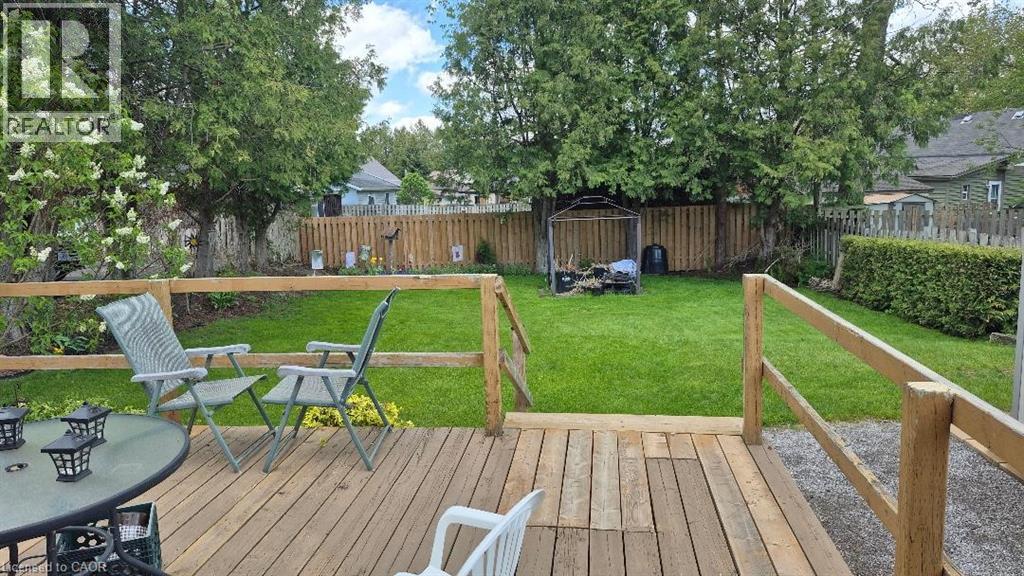 Expansive backyard featuring a wood deck, manicured lawn, and mature trees - 257 Cedar Street, Simcoe, ON - Outdoor With Deck Patio Veranda With Backyard