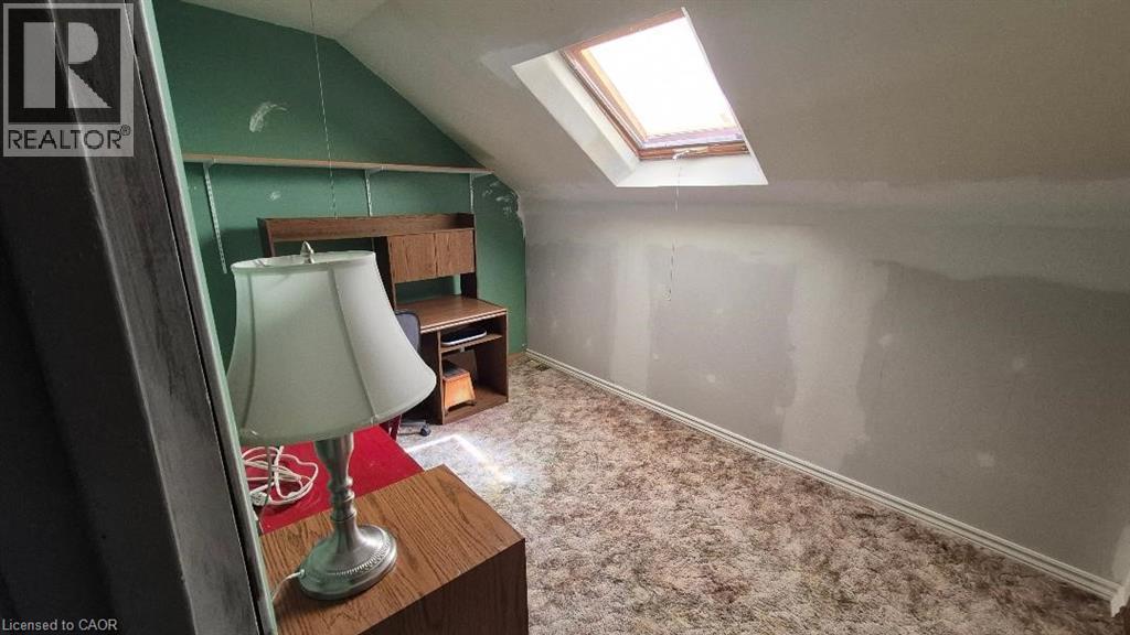 Attic space featuring a skylight, sloped ceiling, and textured carpet flooring suitable for bedroom or office. - 257 Cedar Street, Simcoe, ON - Indoor Photo Showing Other Room