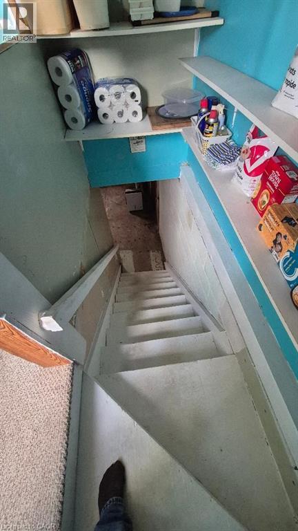 Stairwell featuring white-painted steps, a light blue wall, and white wall-mounted shelving leading to basement. - 257 Cedar Street, Simcoe, ON - Indoor Photo Showing Other Room