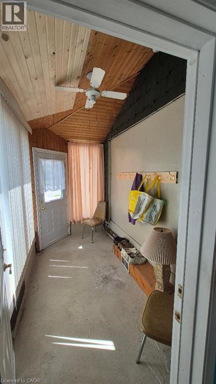 Enclosed porch featuring a sloped wood-finish plank ceiling, a ceiling fan, concrete flooring, and a white entry door with frosted glass - 257 Cedar Street, Simcoe, ON - Indoor Photo Showing Other Room