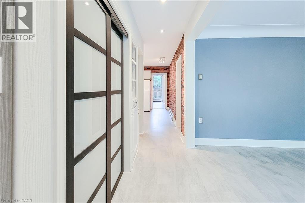 Corridor with brick wall and light wood-type flooring. - 156 Park Row S, Hamilton, ON - Indoor Photo Showing Other Room