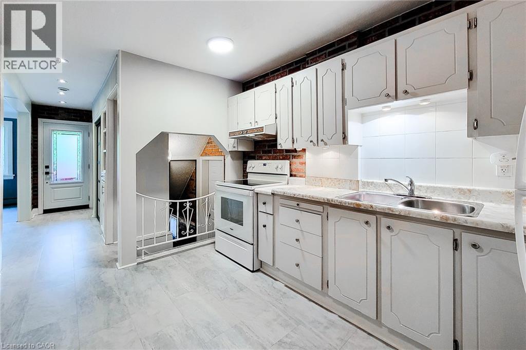 Kitchen with electric range, light countertops, white cabinetry, under cabinet range hood, and backsplash - 156 Park Row S, Hamilton, ON - Indoor Photo Showing Kitchen With Double Sink