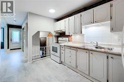 Kitchen with electric range, light countertops, white cabinetry, under cabinet range hood, and backsplash -