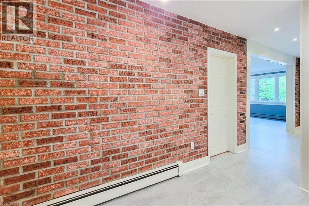 Hall featuring baseboard heating, brick wall, recessed lighting, and a baseboard heating unit - 156 Park Row S, Hamilton, ON - Indoor Photo Showing Other Room