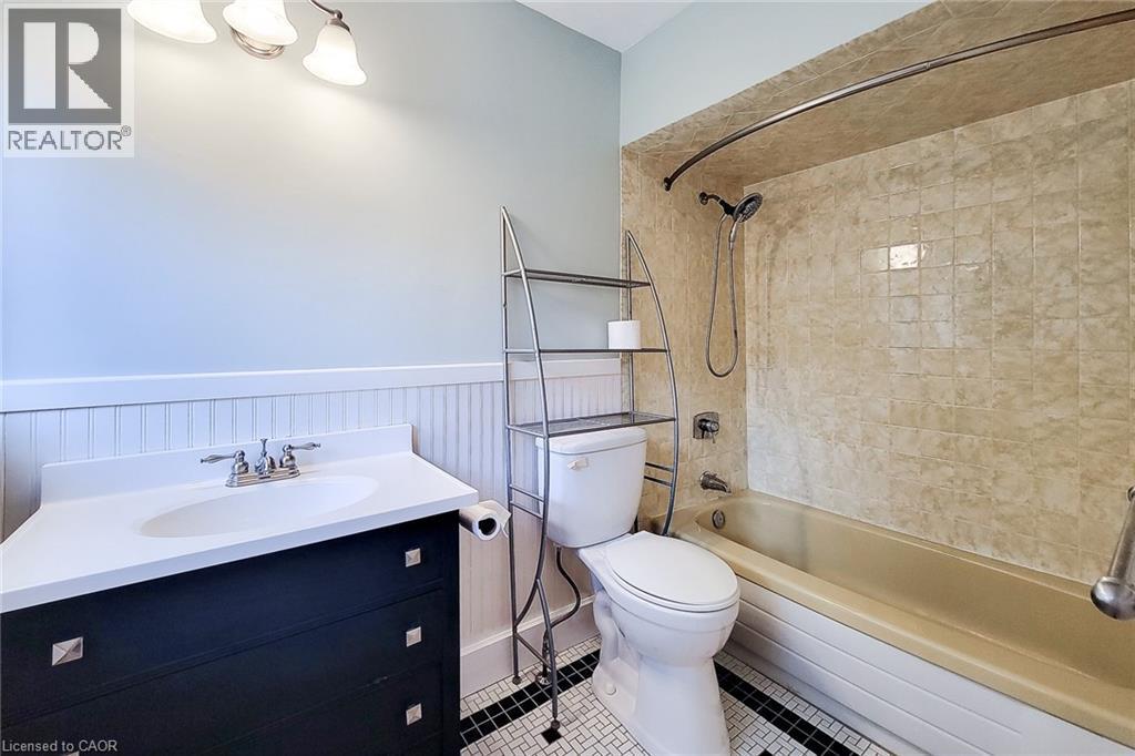 Full bathroom with wainscoting, tub / shower combination, vanity, and tile patterned flooring - 156 Park Row S, Hamilton, ON - Indoor Photo Showing Bathroom
