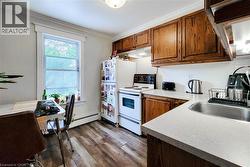 Kitchen featuring white range with electric stovetop, decorative backsplash, crown molding, dark wood finished floors, and under cabinet range hood. -