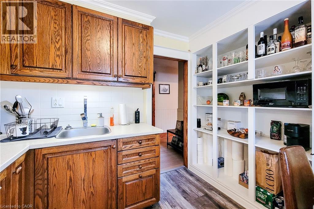Upper Kitchen with ornamental molding, brown cabinetry, dark wood-style floors, black microwave, and light countertops - 156 Park Row S, Hamilton, ON - Indoor