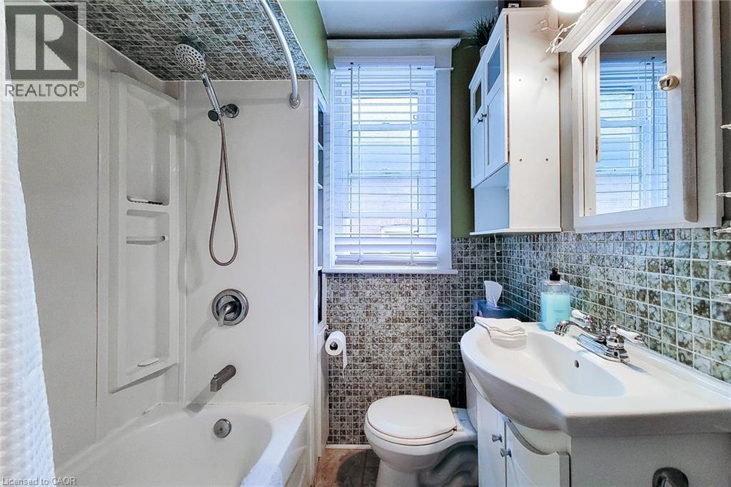 Upper Bathroom featuring healthy amount of natural light, vanity, tile walls, and washtub / shower combination - 156 Park Row S, Hamilton, ON - Indoor Photo Showing Bathroom