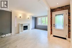 Foyer entrance with a glass covered fireplace, brick wall, and light flooring. -