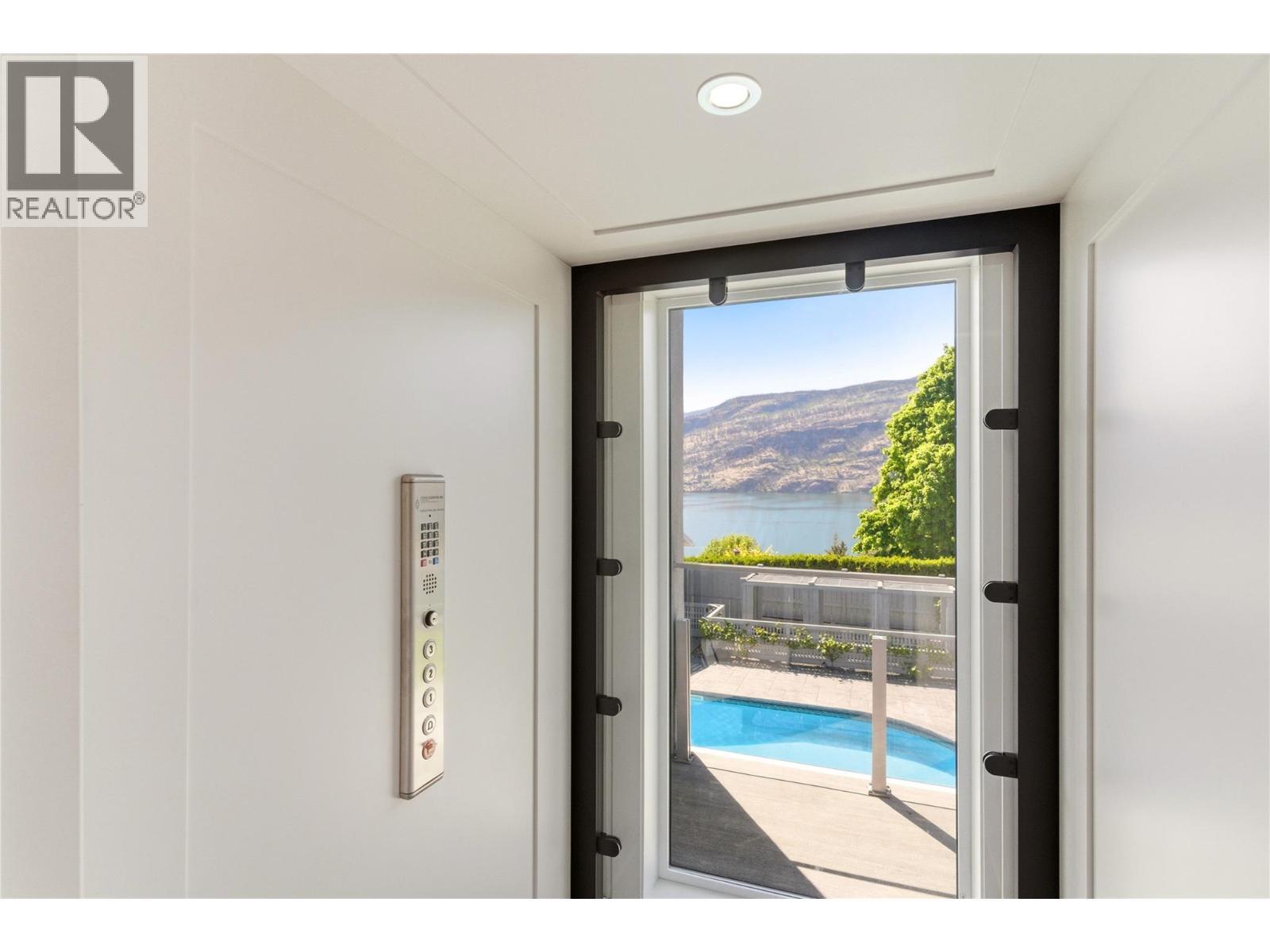 Glass elevator that connects all 3 levels of the home - 2090 Bennett Road, Kelowna, BC - Photo Showing Other Room With In Ground Pool