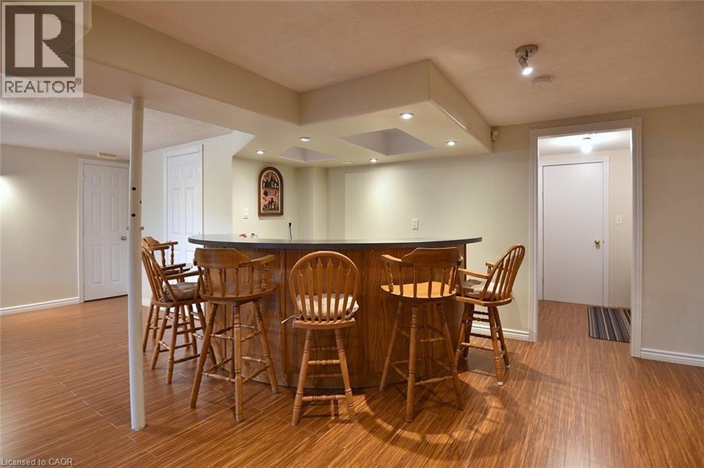 Wood-finish flooring extending throughout a finished lower level, featuring a built-in bar with a dark countertop and recessed lighting - 36 Tommar Place, Hamilton, ON - Indoor Photo Showing Dining Room