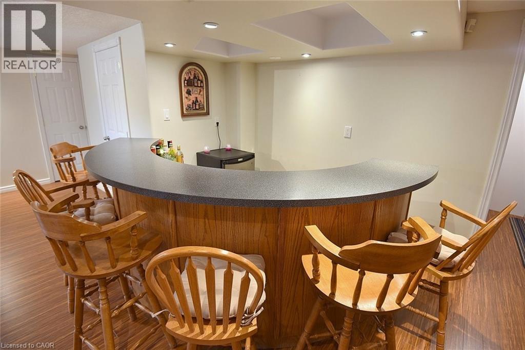 Curved wood-finish bar featuring a dark countertop, recessed lighting, and wood-finish flooring - 36 Tommar Place, Hamilton, ON - Indoor