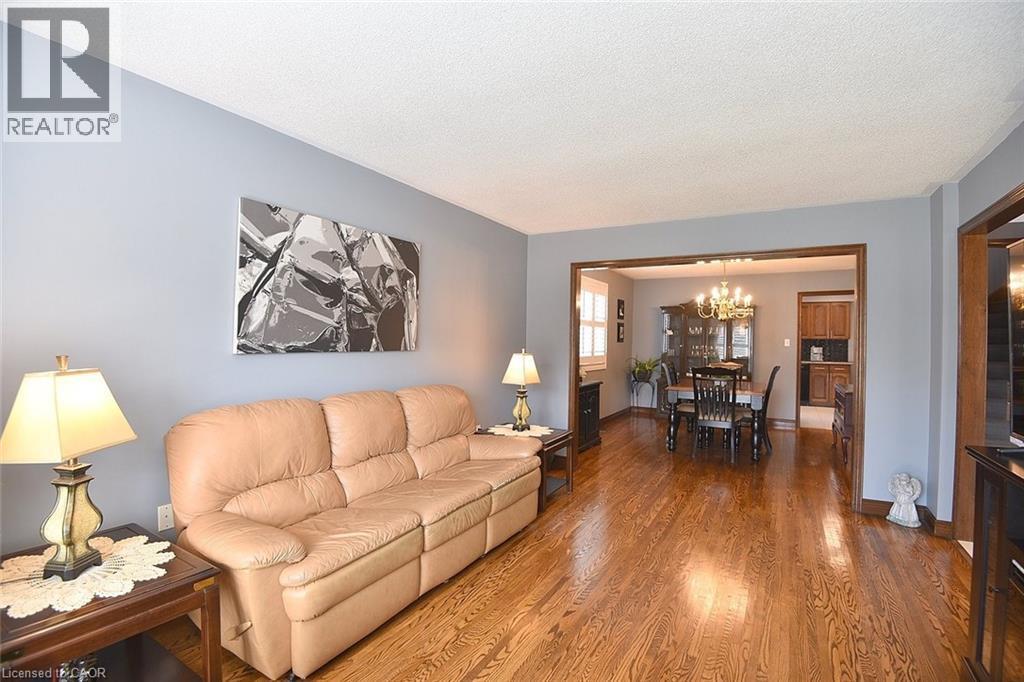 Open-concept living space featuring wood-finish flooring, light blue wall paint, and a white ceiling - 36 Tommar Place, Hamilton, ON - Indoor Photo Showing Living Room