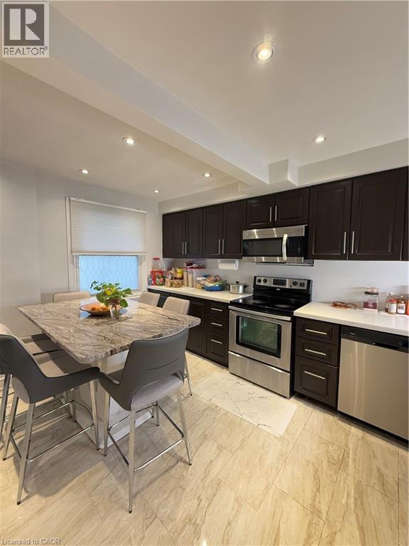 Modern kitchen featuring dark wood-finish cabinetry, stainless steel appliances, and light-toned, veined tile flooring - 181 Thaler Avenue, Kitchener, ON