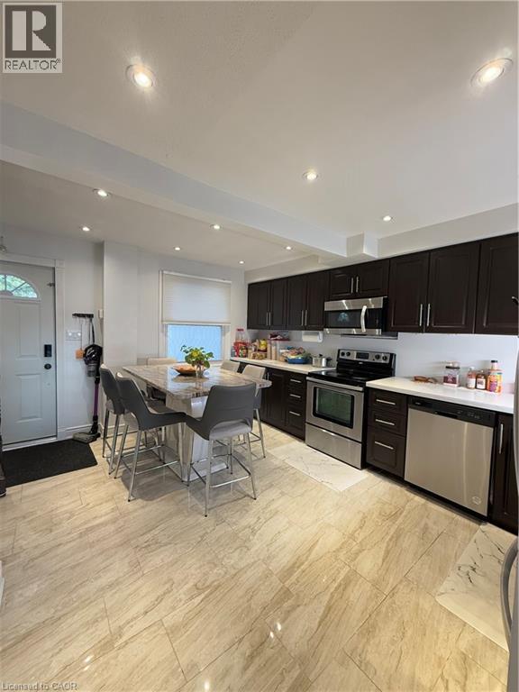 Kitchen featuring wood-finish cabinetry, stainless steel appliances, a center island with seating, recessed lighting, and large format tile flooring - 181 Thaler Avenue, Kitchener, ON