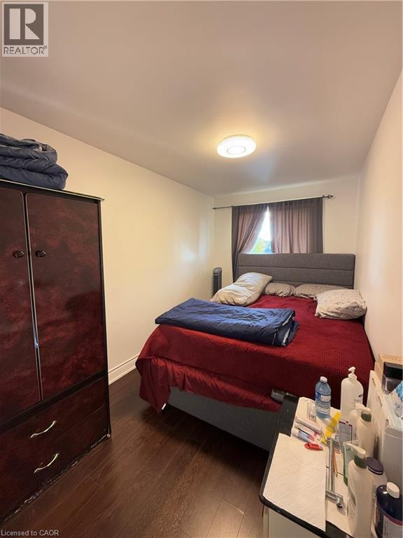 Room featuring wood-finish flooring, white walls, and a window with dark drapery - 181 Thaler Avenue, Kitchener, ON