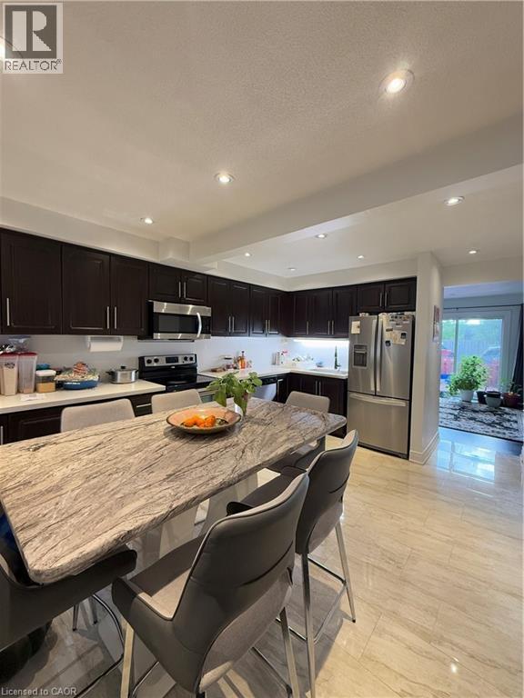 Kitchen featuring dark wood cabinetry, white countertops, recessed lighting, and stainless steel appliances - 181 Thaler Avenue, Kitchener, ON