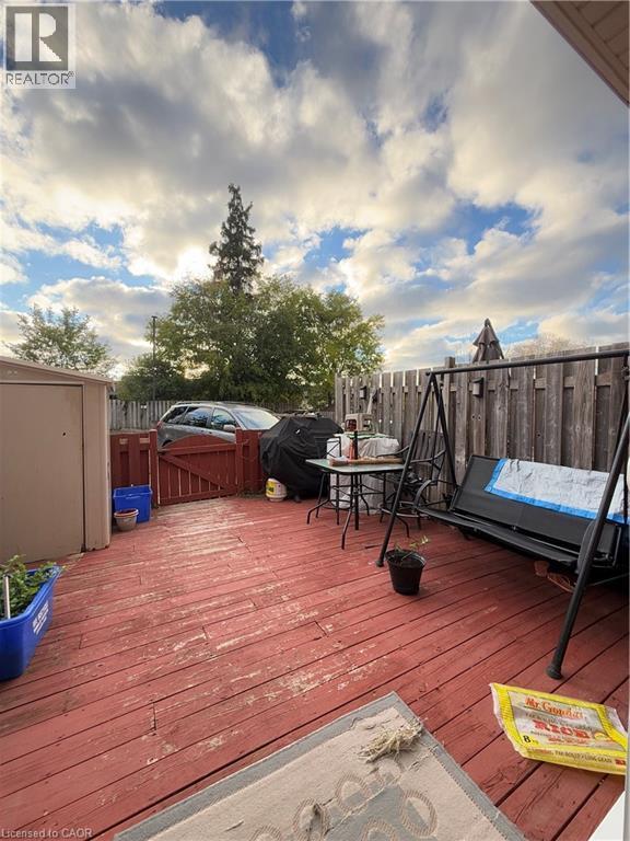 Expansive red-stained wood deck featuring a privacy fence and a storage shed - 181 Thaler Avenue, Kitchener, ON