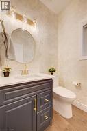 Powder room featuring a vanity with a dark gray base and gold-tone hardware, a white countertop with an undermount sink, and a gold-tone faucet -