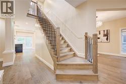 Staircase with light wood-finish treads and risers, complemented by a black wrought iron and wood-finish railing -