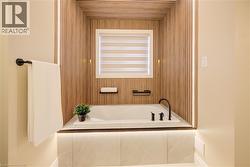 Soaking tub with sleek black fixtures, set within a wood-slatted alcove featuring integrated lighting -