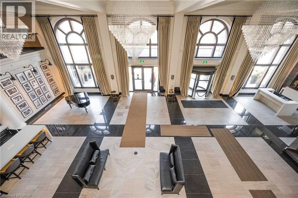 Expansive foyer featuring a mosaic tile floor, multiple chandeliers, and tall arched windows with drapes - 112 King Street E Unit# 907, Hamilton, ON