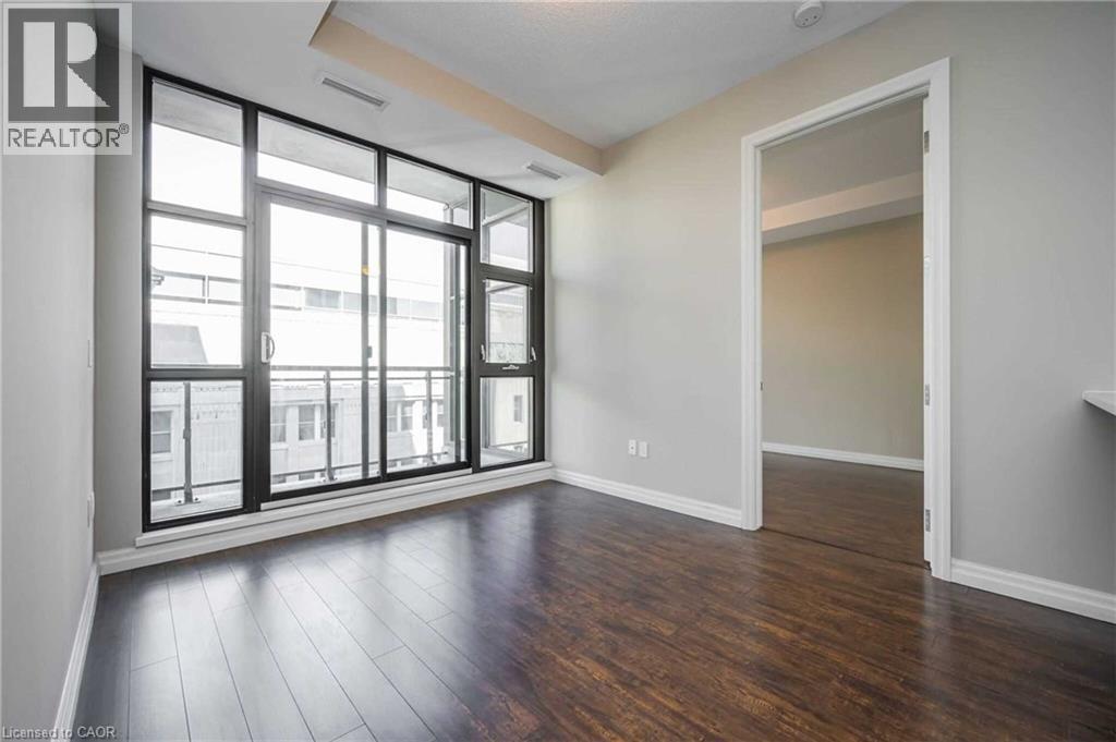 Expansive room featuring a wall of floor-to-ceiling windows with sliding glass door access to an outdoor balcony - 112 King Street E Unit# 907, Hamilton, ON