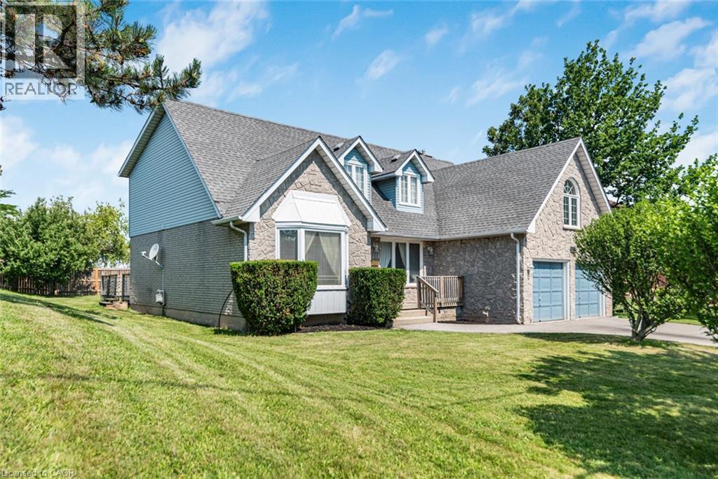 Stone and siding exterior featuring a multi-gable roofline, bay window, and a two-car garage with arched doors - 381 Kerman Avenue, Grimsby, ON - Outdoor