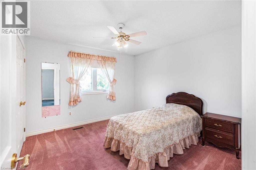 Bedroom featuring a window with a sheer curtain, a ceiling fan with integrated lighting, white walls, and pink carpeting - 381 Kerman Avenue, Grimsby, ON - Indoor Photo Showing Bedroom