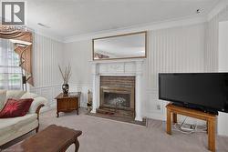 Formal living area featuring a brick fireplace with a white mantel, textured wallpaper, crown molding, and wainscoting -