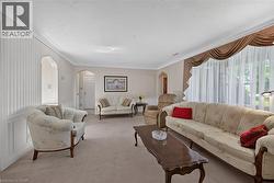 Spacious living area featuring neutral carpeting, crown molding, and wainscoting -